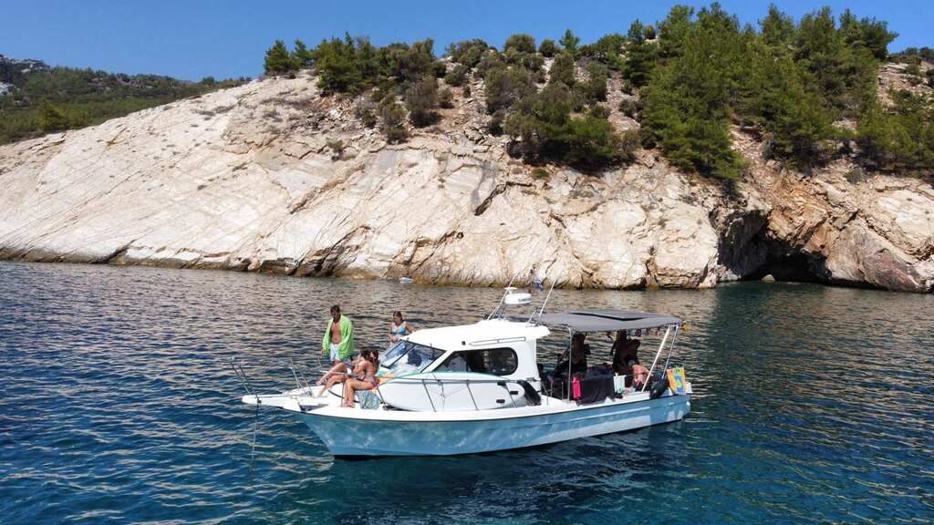 Cretamare 10 anchored below white cliffs with guests relaxing on board