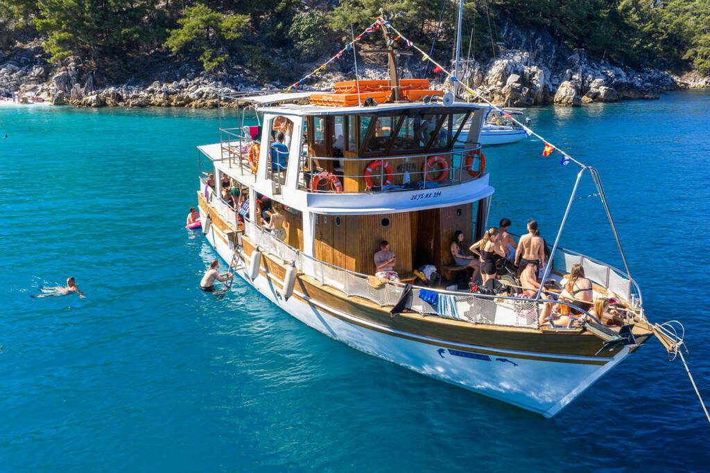 Traditional Greek Boat 17 from above in turquoise water with swimmers beside it